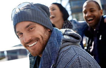 outdoor portrait of happy young man wearing scarf and smiling at camera