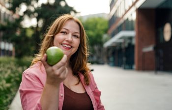 Plus size woman holding green apple.